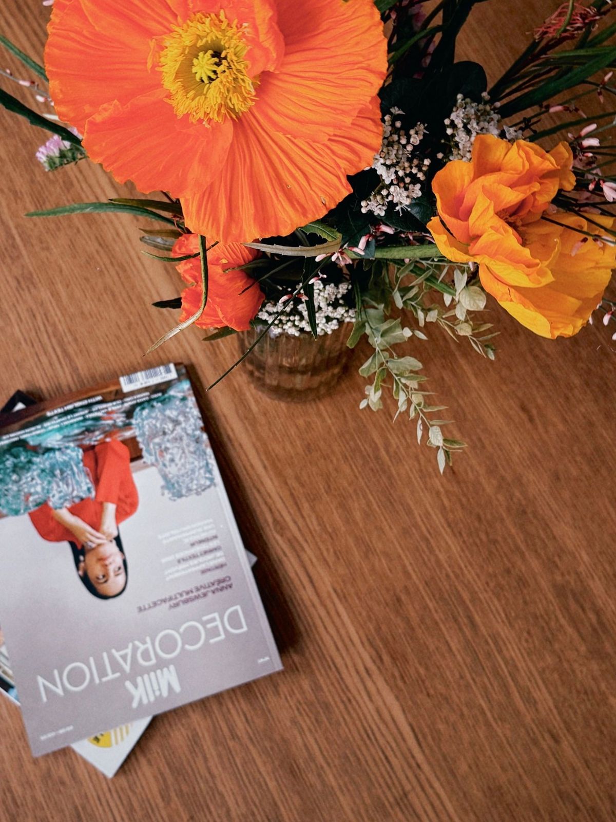 Bouquet de pavots et fleurs des champs sur une table en bois, magazines posés à côté