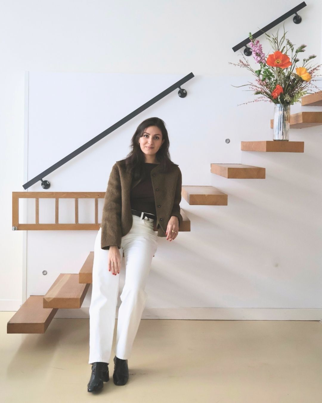 Portrait d'Anaïs Sihamdi assise sur un escalier en bois, bouquet de pavots
