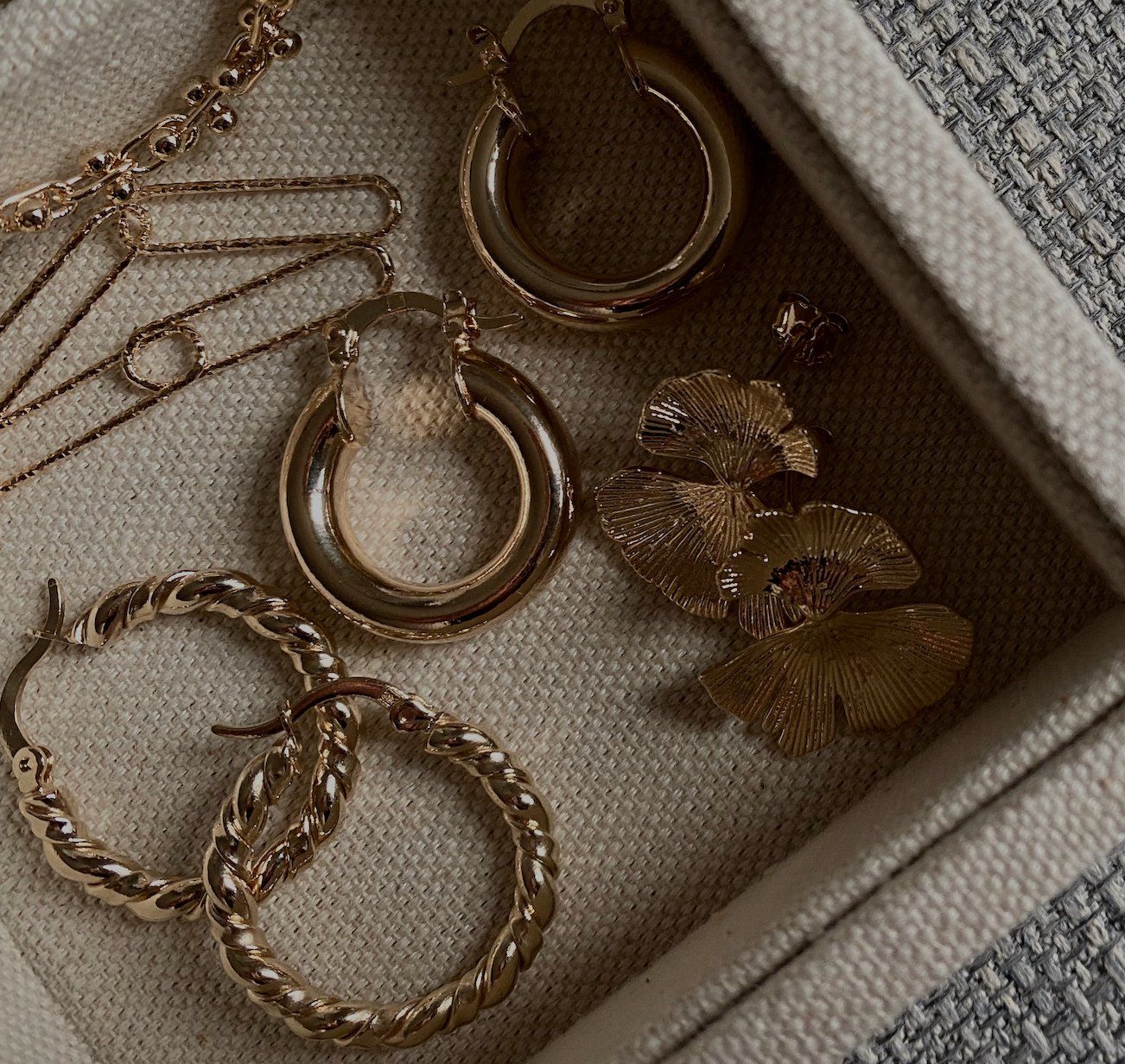 Bijoux Piaola : créoles et boucles dorées sur lin